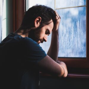 Upset man looking out a window